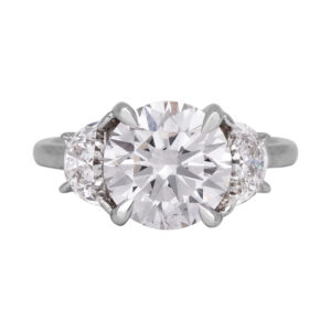 white gold 3-stone engagement ring centered with a large round brillianrt diamond flanked by half moon diamonds