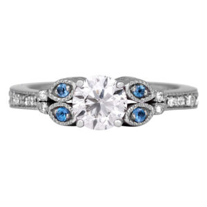 white gold engagement ring centered with a round brilliant diamond flanked by four round brilliant aquamarines with round brilliant diamonds in the band