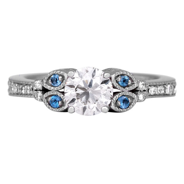 white gold engagement ring centered with a round brilliant diamond flanked by four round brilliant aquamarines with round brilliant diamonds in the band