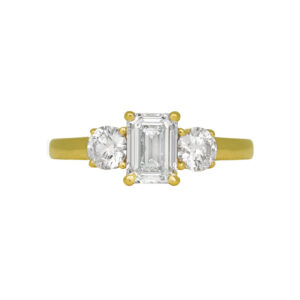 yellow gold 3-stone ring centered with an emerald cut diamond flanked by two round diamonds