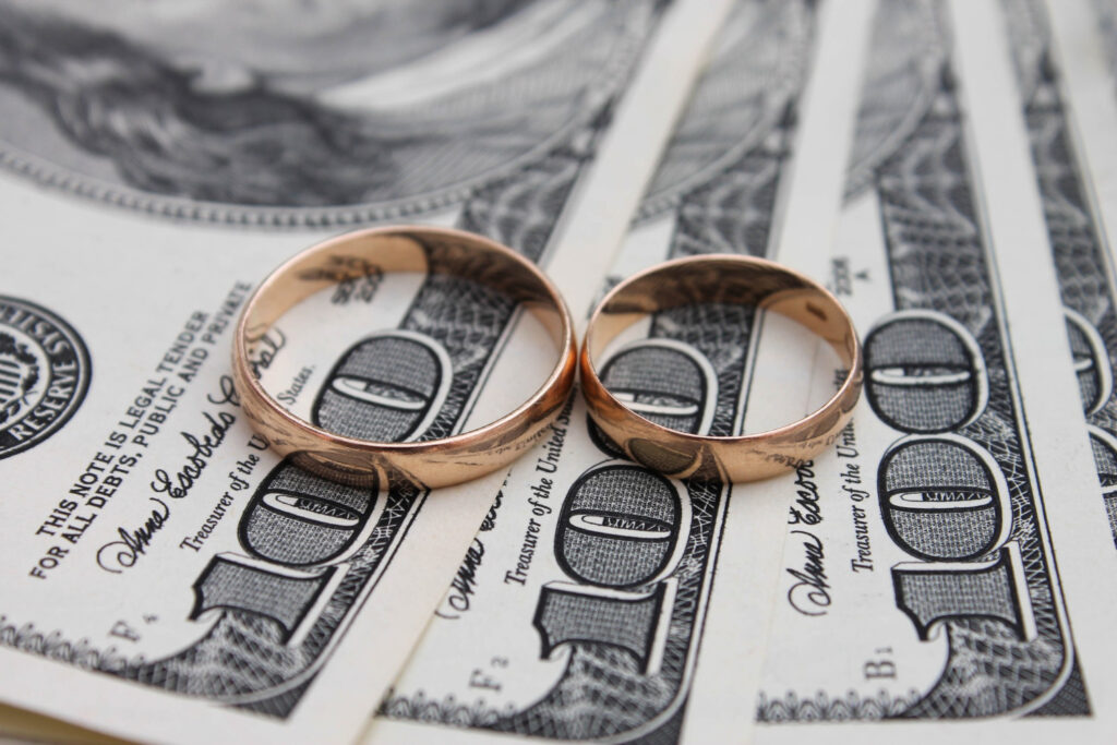 2 Wedding Rings on Top of 3 $100 Bills