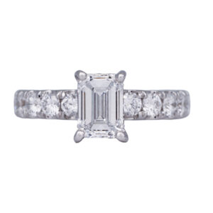 white gold under halo ring set with an emerald cut diamond & round diamonds in the band