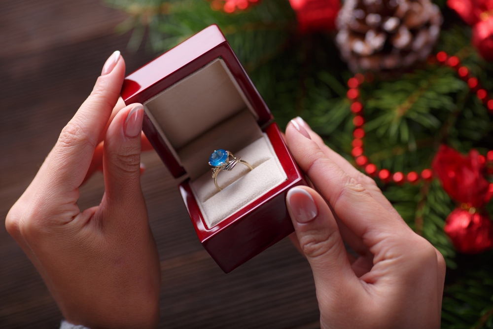 A hand opening a red jewelry box with a ring inside