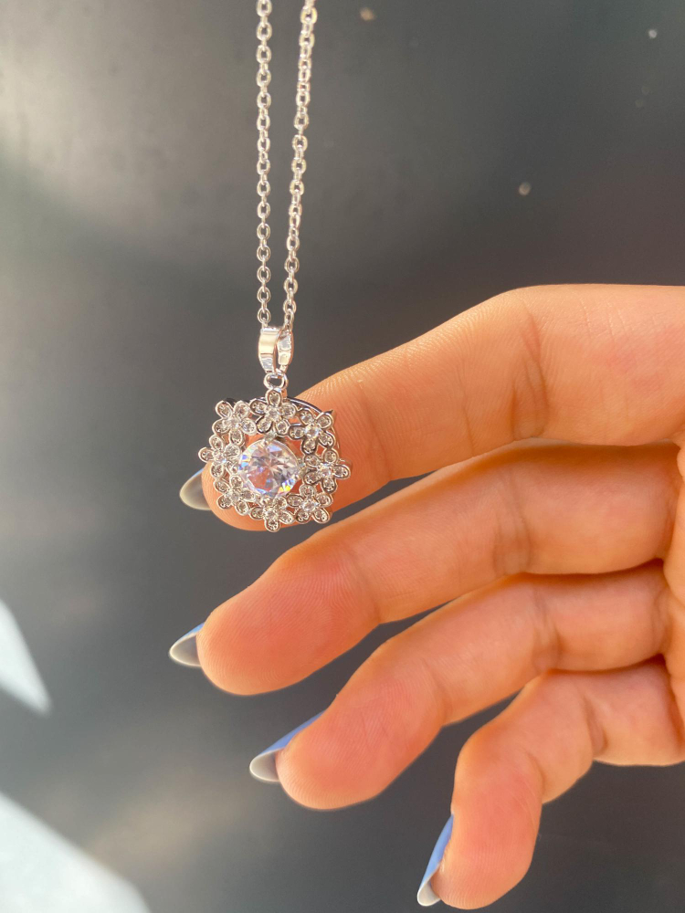 A woman's hand touching a hanging pendant of a jewelry necklace