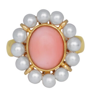 yellow gold ring centered with a cabochon oval coral surrounded by a pearl halo