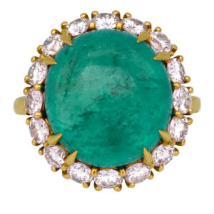 yellow gold halo ring centered with a large round cabochon emerald surrounded by round brilliant diamonds.