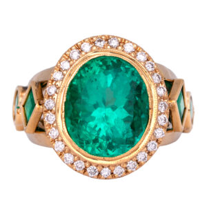 yellow gold halo ring centered with a large oval Colombian emerald surrounded by round diamonds with square and round emeralds in the band