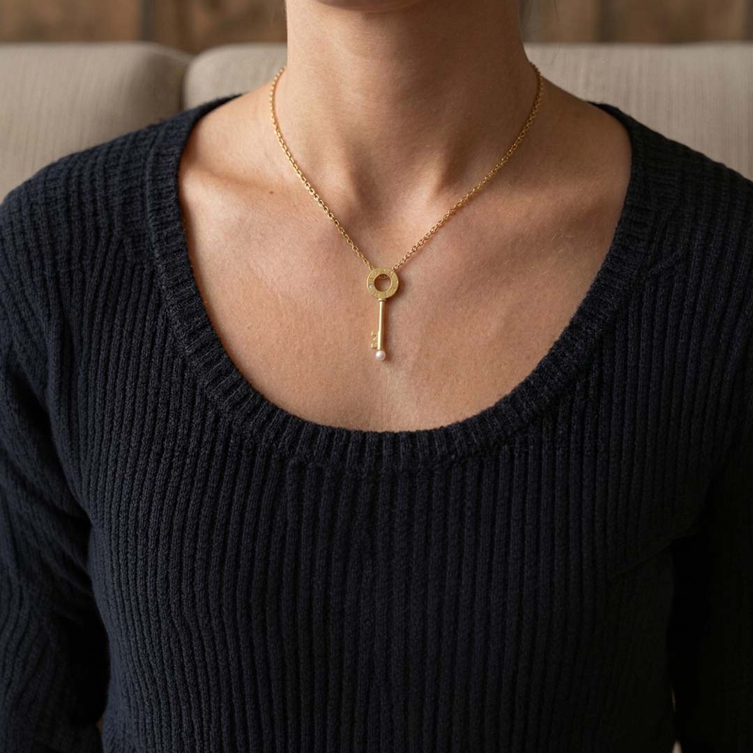 a woman wearing a yellow gold pendant with a key set with a diamond and pearl