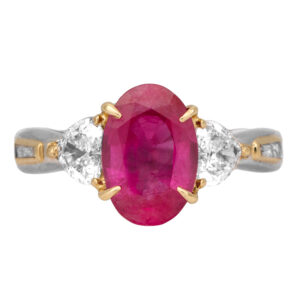 yellow gold and platinum ring centered with an oval ruby flanked by heart and baguette diamonds