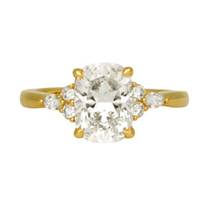 yellow gold ring centered with an elongated cushion diamond flanked by round diamonds