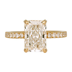 yellow gold engagement ring centered with a radiant diamond surrounded by round diamonds in the band and under-halo