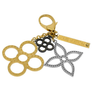 gold tone, silver, and black Louis Vuitton key charm featuring circle and flower shapes