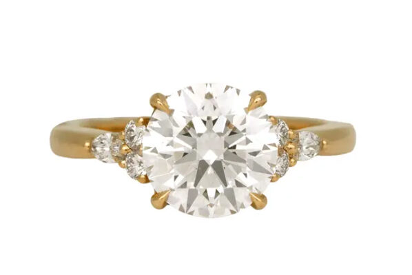 yellow gold engagement ring centered with a large round diamond flanked by round and marquise diamonds