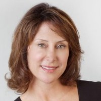 a smiling woman in front of a lake or bay