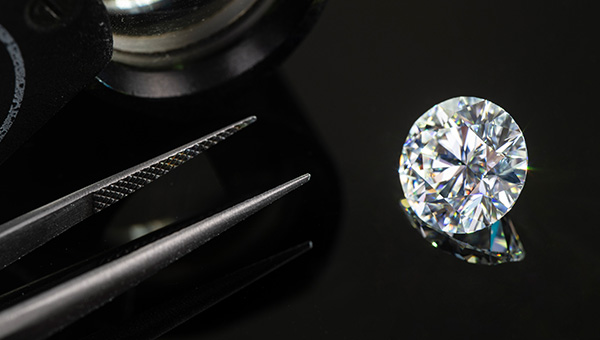 an image of a lab-grown diamond next to a pair of tweezers resting on a table