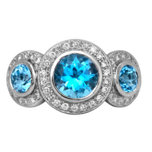 Vintage 18k white gold halo three stone ring set with 3.00 carats of round brilliant blue topazes plus 0.45 carats of round brilliant earth-mined diamonds.