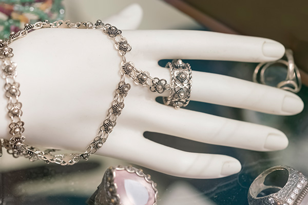 a close up photo of a mannequin hand wearing a vintage piece of jewelry that connects a bracelet to a ring.