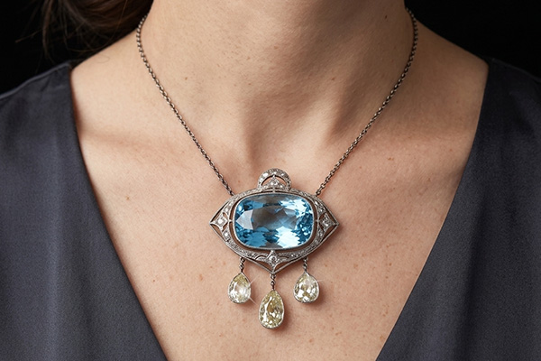 a close-up image of a woman wearing an aquamarine and diamond necklace.