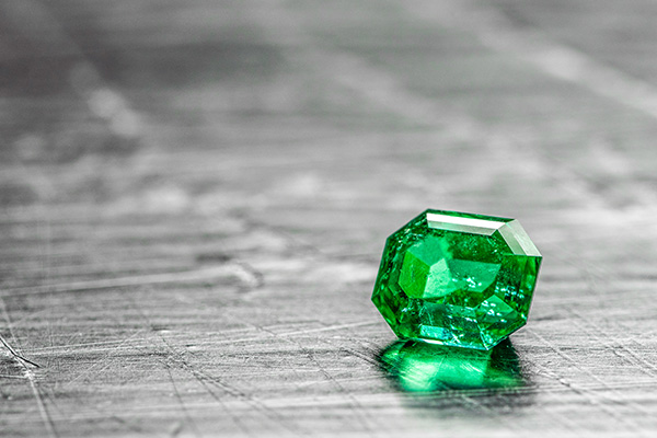 a close up image of a loose emerald gemstone.