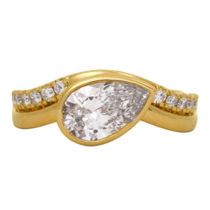 New 14k yellow gold East-West engagement ring set with a 1.46 carat pear lab-grown diamond plus 0.33 carats of round brilliant lab-grown diamonds. In an "East-West" setting, the center diamond is set horizontally across the finger rather than the traditional "North-South" orientation. Especially effective for elongated shapes such as oval, marquise, and emerald cuts.