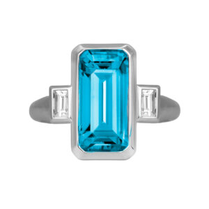 New 18k white gold three stone ring set with a 6.71 carat emerald cut blue zircon plus 0.29 carats of emerald cut earth-mined diamonds.