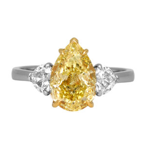 Vintage platinum and 18k yellow gold three stone engagement ring set with a 3.01 carat fancy yellow pear earth-mined diamond plus 0.75 carats of heart earth-mined diamonds.