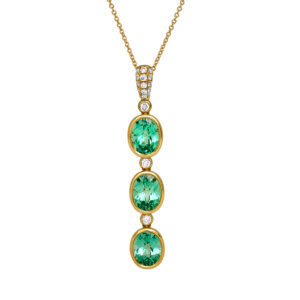 New 18k yellow gold Chatham pendant set with 7.07 carats of lab-grown oval chrysoberyl & 0.32 carats of lab-grown round brilliant diamonds. Shown on a 14k yellow gold cable chain with a spring clasp.