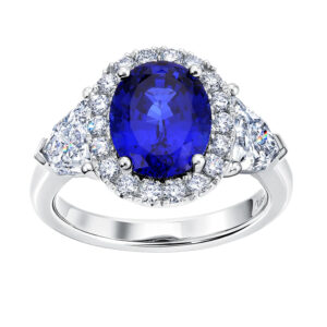 New 18k white gold Chatham halo ring set with a 3.68 carat oval lab-grown blue sapphire plus 1.99 carats of lab-grown pentagon and round brilliant diamonds.